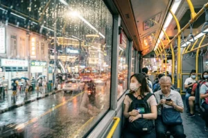 Singapore bus interior at night with commuters and rainy street view.